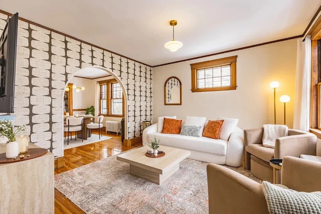 Living room after the design transformation, with coordinated seating, layered textiles, and a statement wall