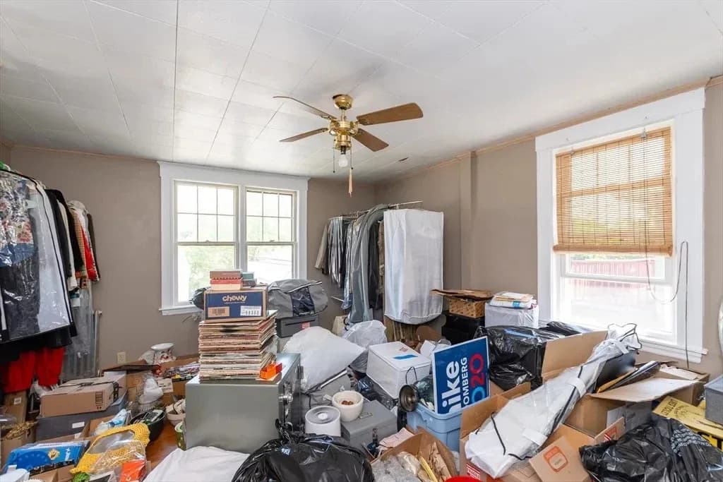 Guest bedroom before the design transformation, filled with storage and clothing racks