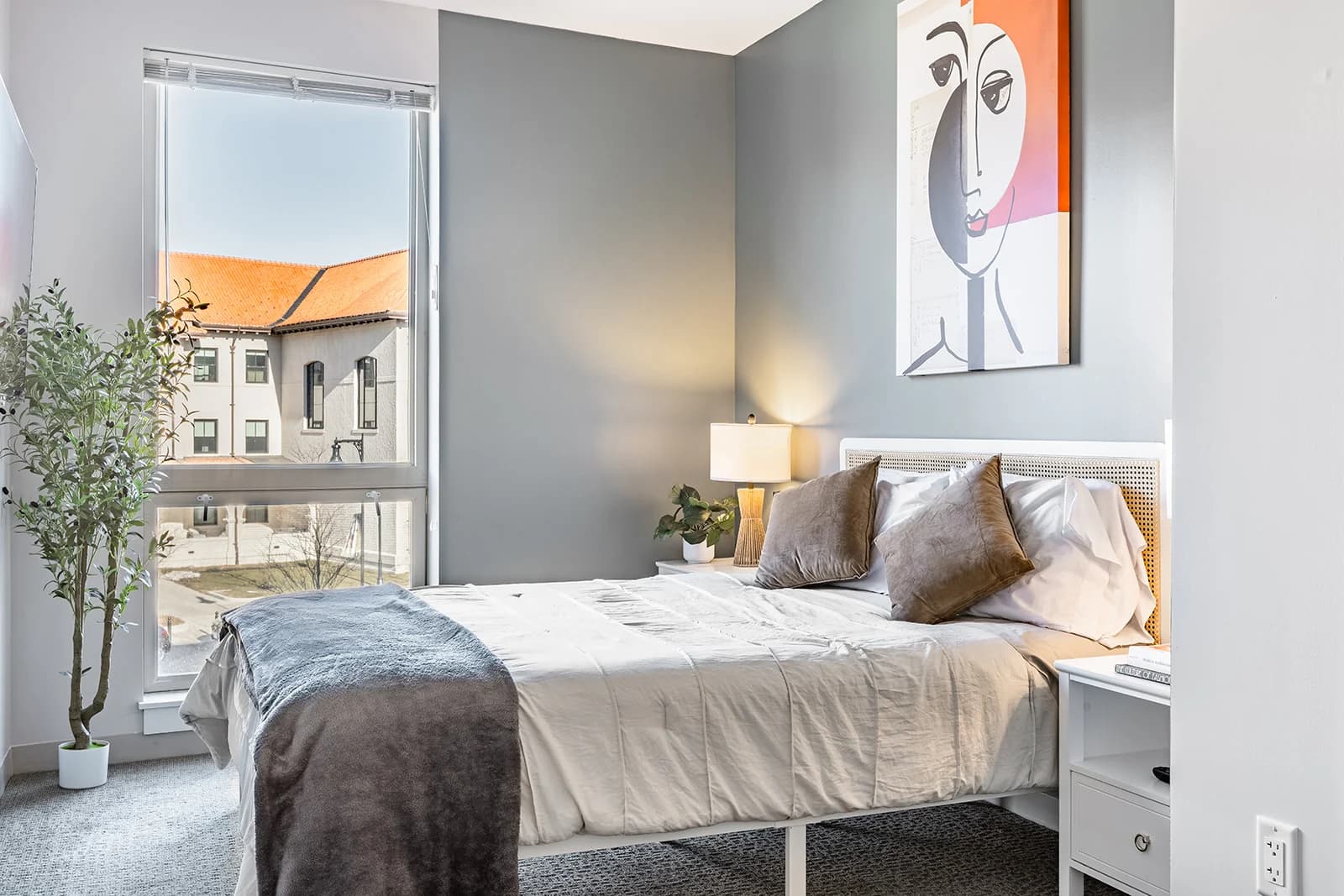 Furnished bedroom in an R Living apartment with layered bedding and warm lighting